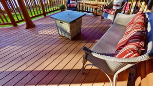 Una terraza de madera con un sofá de mimbre, una mesita y una silla.