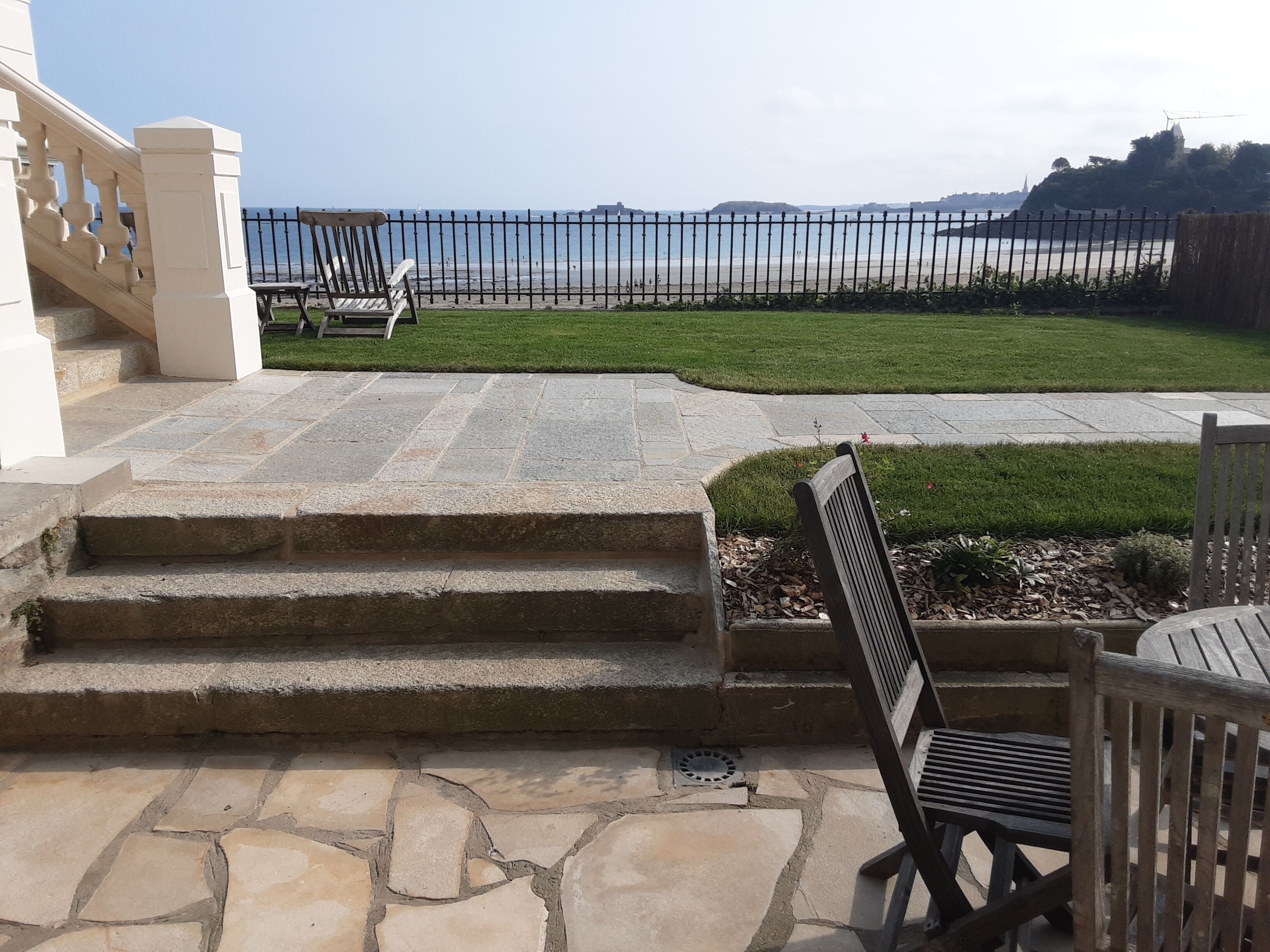 A stone staircase leading to a grassy area with a view of the sea.