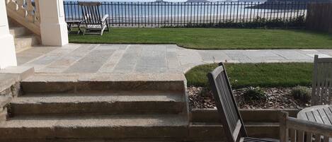 A stone staircase leading to a grassy area with a view of the sea.
