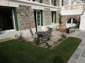 A stone building with a patio area featuring outdoor furniture and a small garden.