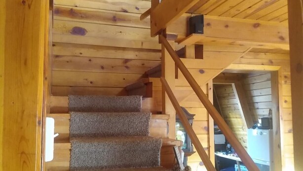 Eine Holztreppe mit Teppichstufen, die zu einer zweiten Etage führt.