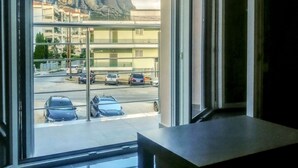 A view from a room with a large window overlooking a parking area and buildings with a rocky mountain in the background.