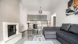 A modern living room with a grey sofa, a white coffee table, and a fireplace.