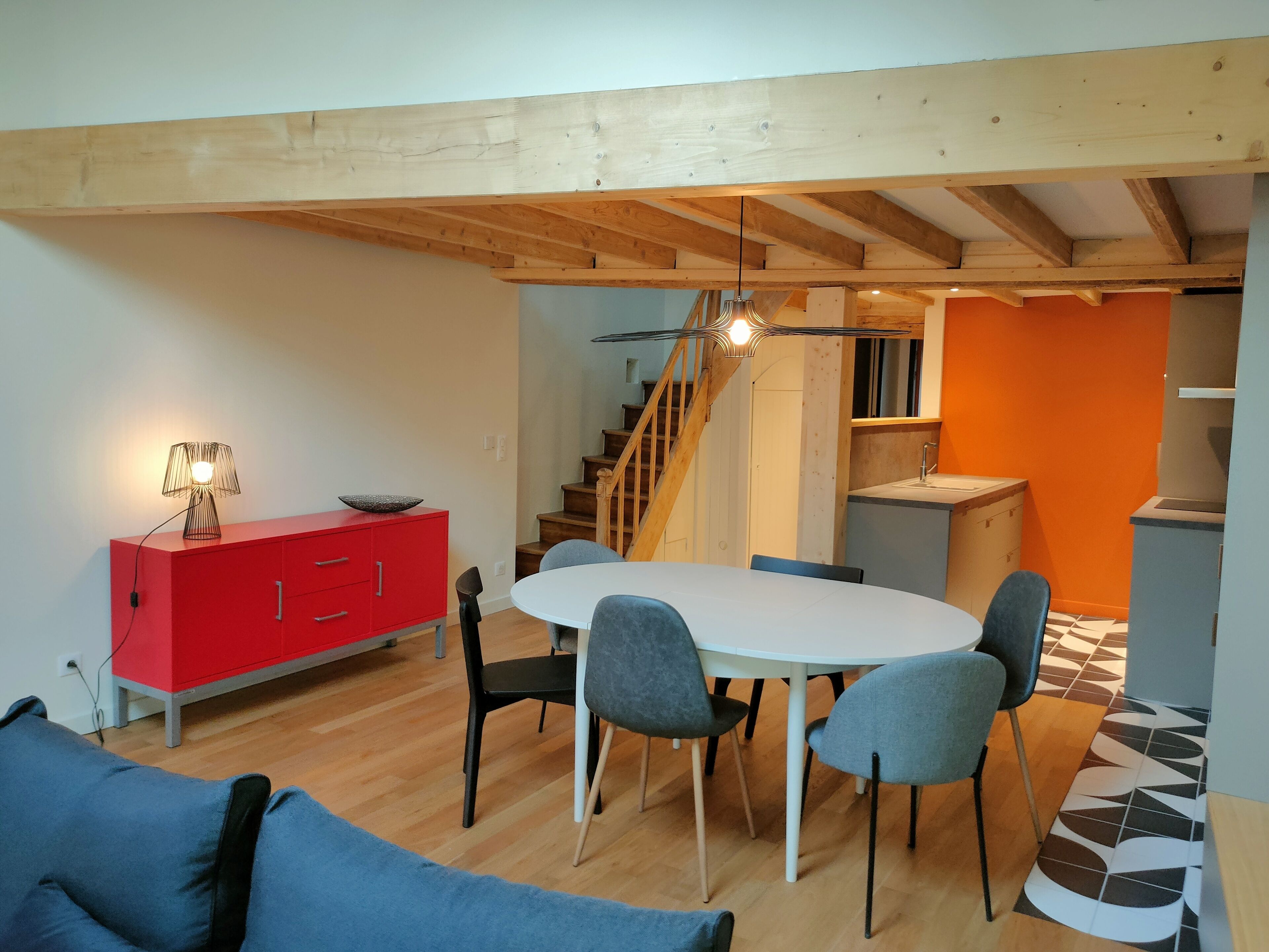 Ein Essbereich mit einem runden Tisch, vier Stühlen, einem roten Schrank und einer Lampe.