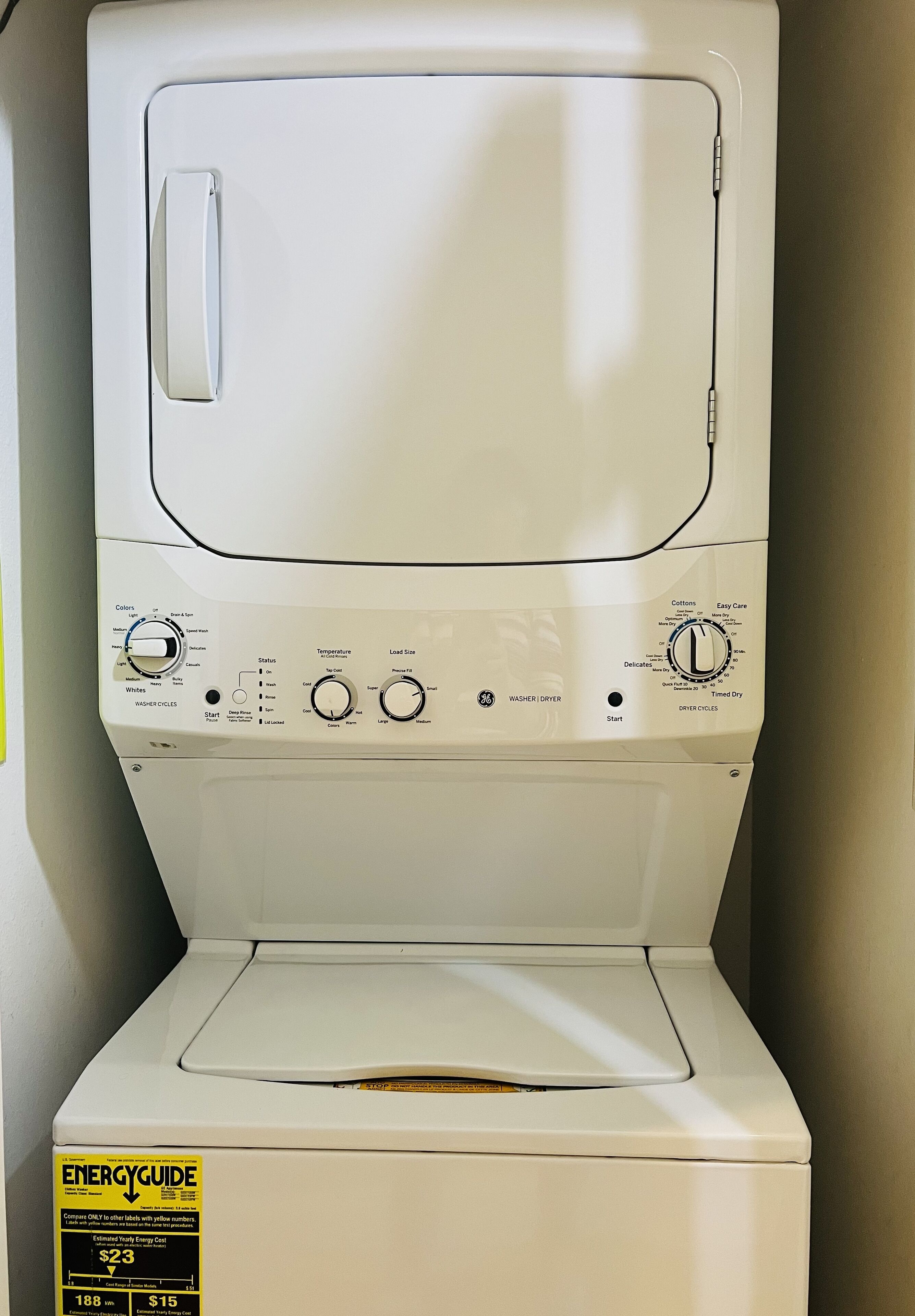 A front view of a white front-loading washer and dryer unit with control knobs and a start button.