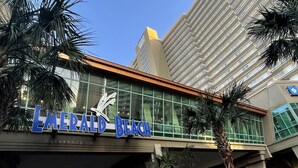 El exterior del hotel Emerald Beach, con una vista clara de la fachada, amplias ventanas y palmeras en primer plano.