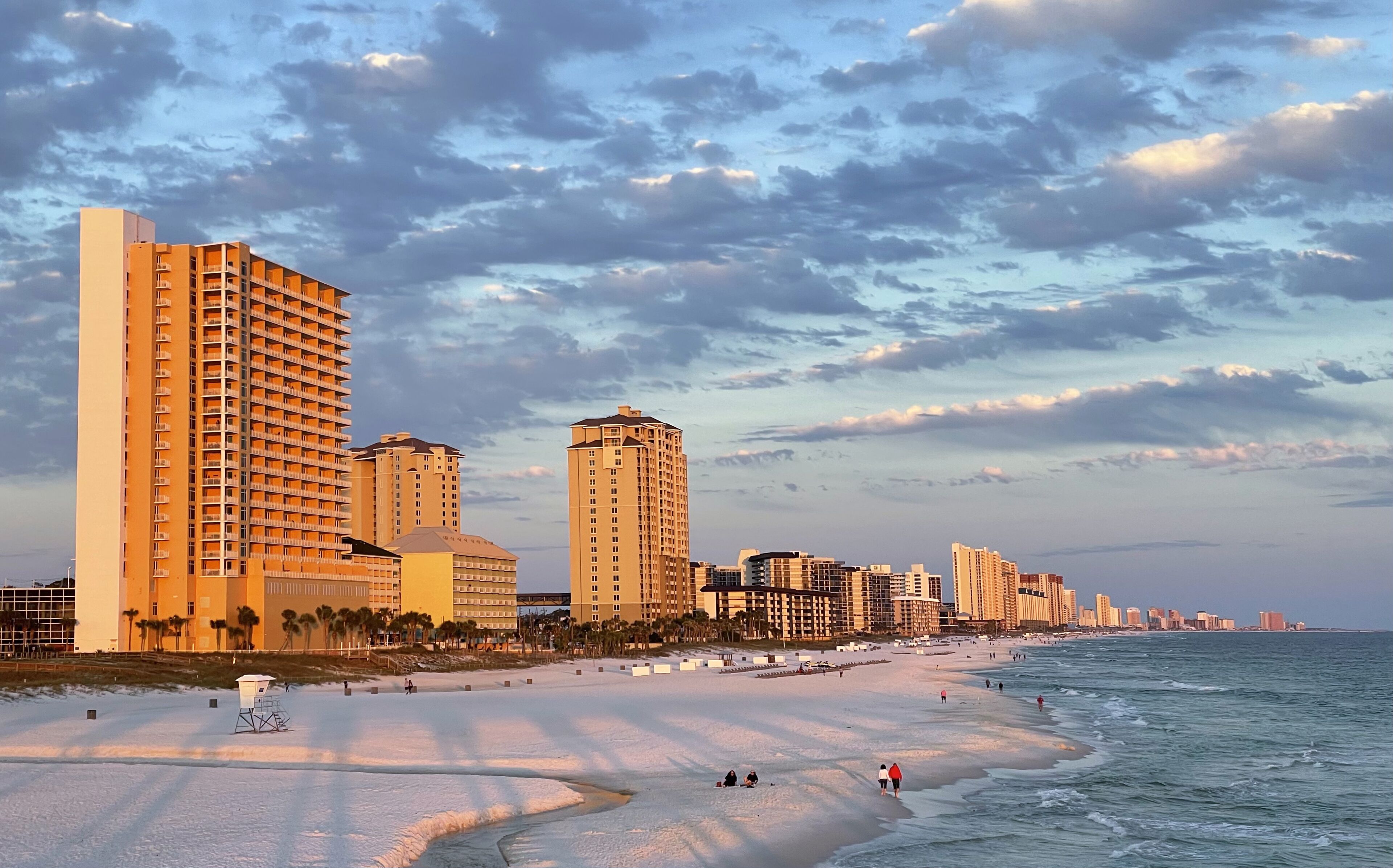 A coastal cityscape with high-rise buildings, a sandy beach, and the ocean.
