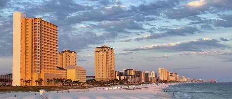 A coastal cityscape with high-rise buildings, a sandy beach, and the ocean.