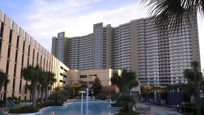 Un hotel con piscina rodeada de tumbonas y palmeras.