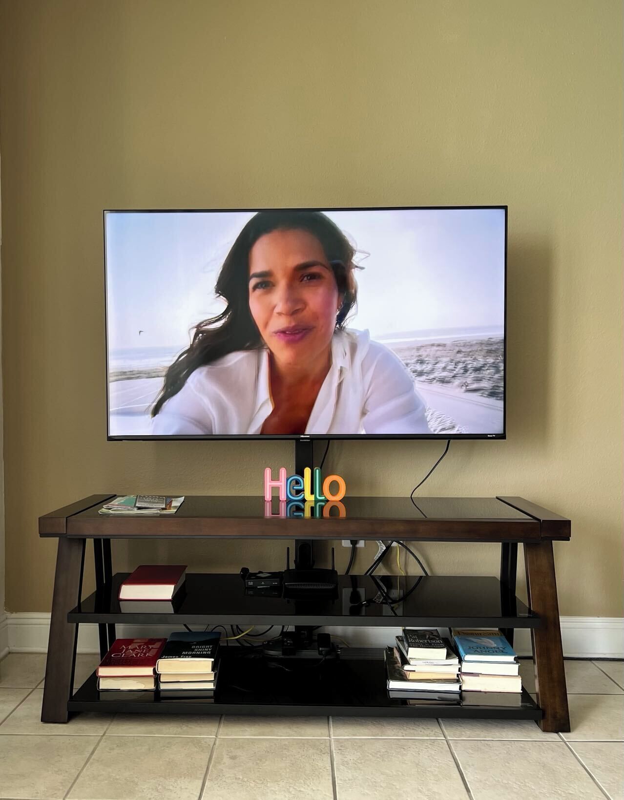 A television on a wooden stand with a shelf below displaying books.