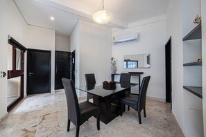 A modern dining area with a glass table, black chairs, and a ceiling light.