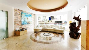 A spacious living room with a large sectional sofa, a decorative rug, and a unique ceiling design. - Beautiful and comfortable apartment in a condominium facing the sea (Playa del Carmen)