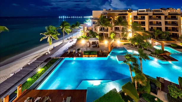 A resort with a large swimming pool, a beach, and a view of the ocean. - Beautiful and comfortable apartment in a condominium facing the sea (Playa del Carmen)