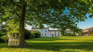 A large, historic building with a well-maintained lawn and a hammock hanging from a tree. - DOMAINE DE CEZAC-Proche Bordeaux-St-Emilion-Arcachon-Blaye (Cezac)