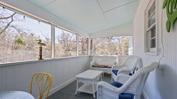 Une véranda couverte, aménagée avec des meubles en osier, une table et une chaise.