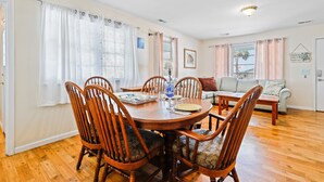 Un coin repas avec une table et des chaises en bois, un canapé et une fenêtre avec des rideaux.