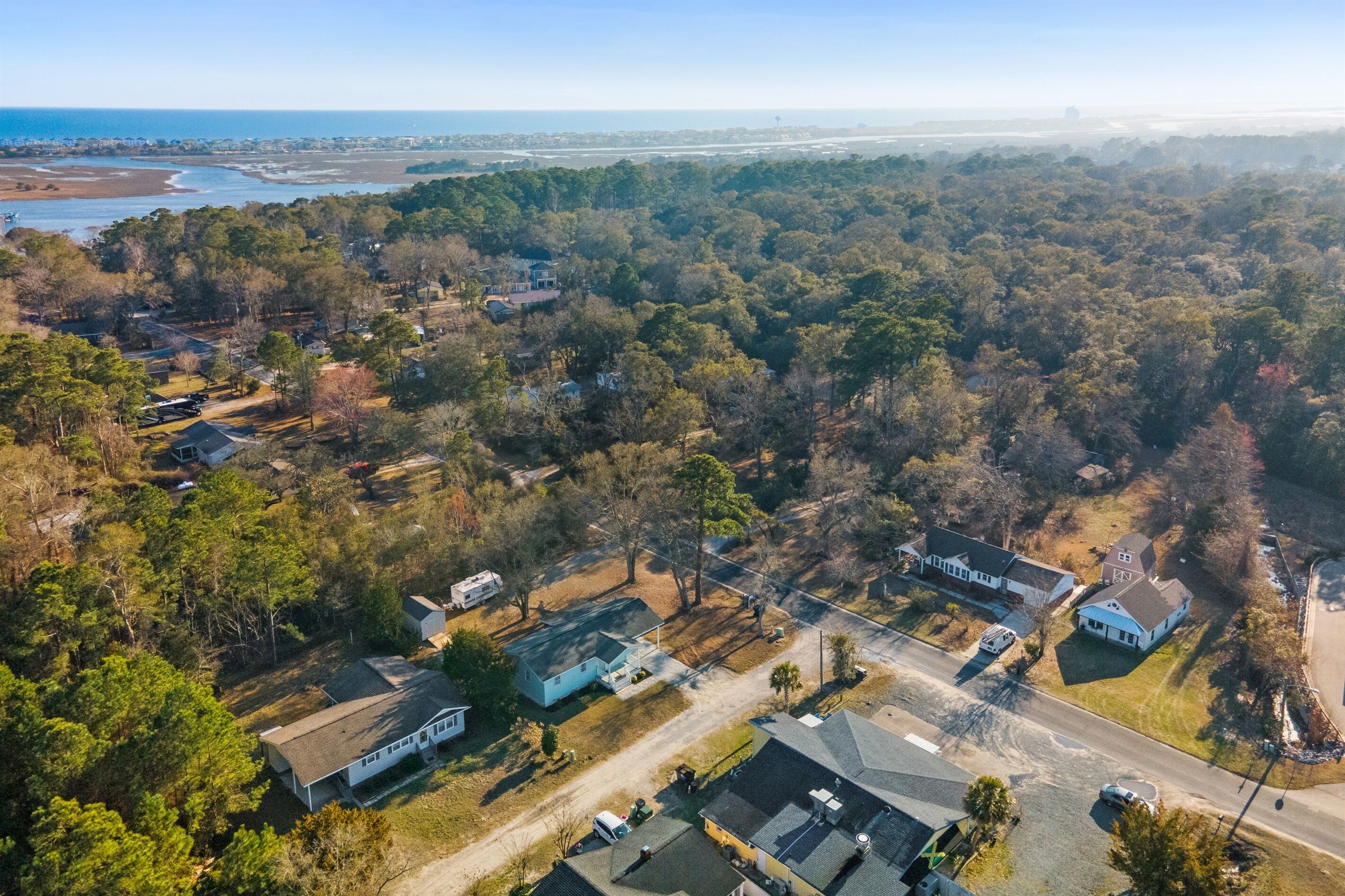 An aerial view of a residential area with houses, roads, and a coastline in the background.