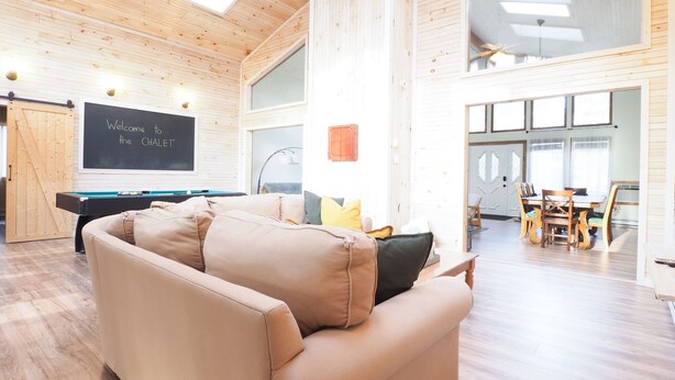 Una habitación amplia con mesa de billar, sofá y comedor con sillas.