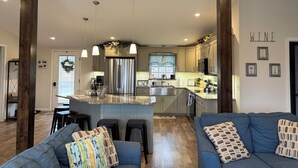 A modern kitchen with a central island, wooden beams, pendant lighting, and a 'WINE' sign on the wall. - Sunrise at the Sawmill - Couples Retreat! (Dundee)