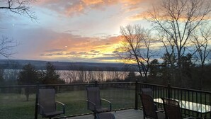A deck with chairs and a table overlooking a lake and distant hills during sunset. - Sunrise at the Sawmill - Couples Retreat! (Dundee)