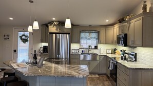 A modern kitchen with a large island, stainless steel appliances, and light wood cabinetry. - Sunrise at the Sawmill - Couples Retreat! (Dundee)