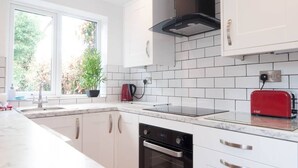 Une cuisine moderne avec des meubles blancs, une hotte noire, un grille-pain rouge et un lave-vaisselle.