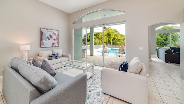 Ein modernes Wohnzimmer mit einem Glastisch, zwei Sofas, einem Pool und Blick ins Freie.