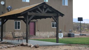 Un bâtiment doté d’un patio couvert, d’un espace extérieur aménagé pour s’asseoir et de fondations en pierre.