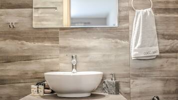 A bathroom with a wooden wall, a white sink, and a towel rack with a white towel labeled "COCO-MAT".