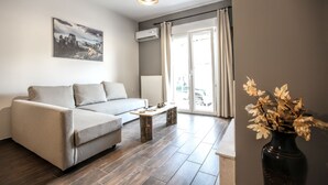 A modern living room with a sofa, a coffee table, and a vase with dried flowers. - Terra di Meteora Suites 2 (Kalabaka)