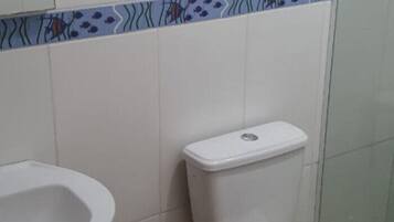 Casa de banho com sanita, bidé e painel de azulejos.
