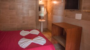 A hotel room with a bed, a wooden bench, a sink, and a TV mounted on the wall. - Hotel Ferrugem Eco Village (Garopaba)