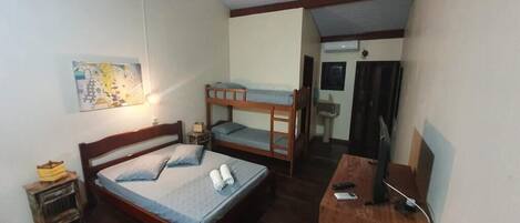 A room with a single bed, a bunk bed, a desk, and a television.