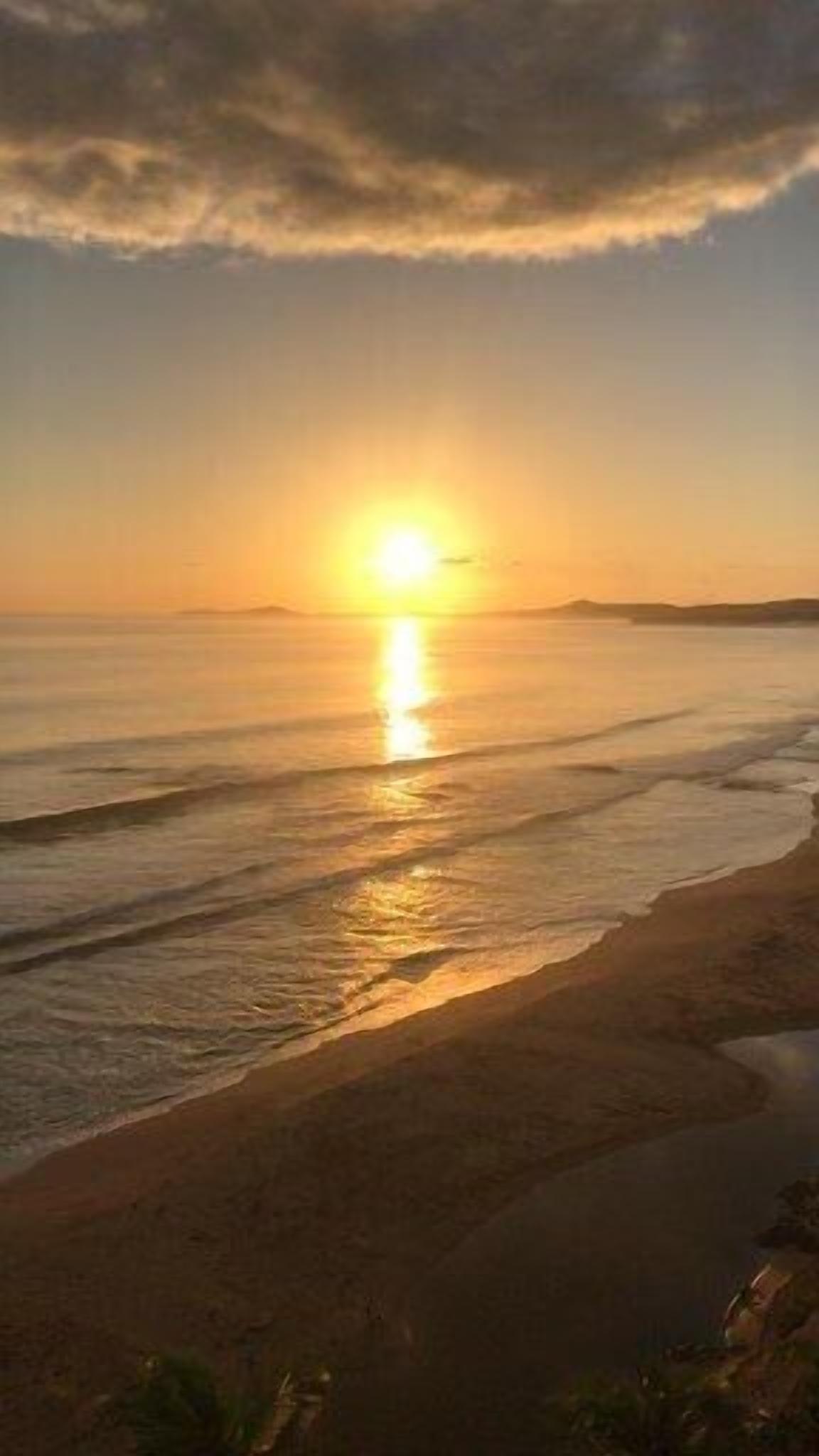 A beach with a sunset over the ocean.