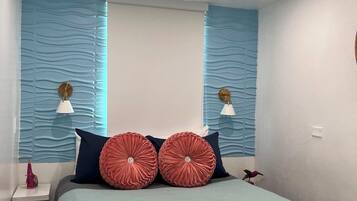 A bedroom with a bed, two wall-mounted lamps, and a window with curtains.
