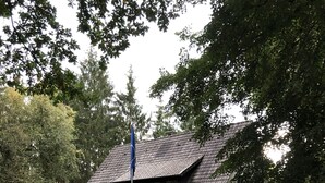 Una casa con tetto spiovente, immersa in un giardino curato con siepi potate e prato.