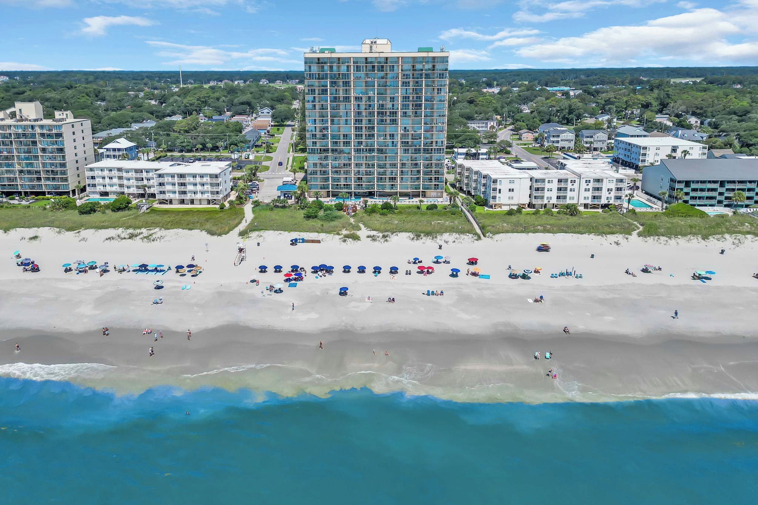 Ein Küstenhotel mit mehreren Gebäuden, einem Sandstrand und Blick auf den Ozean.