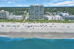 A coastal hotel with multiple buildings, a sandy beach, and a view of the ocean. - Oceanfront Luxury Top Location Lazy River Pool Grills (North Myrtle Beach)