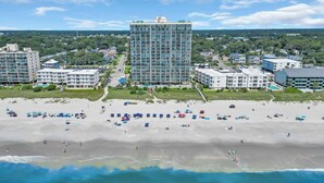 Un hotel costero con varias edificaciones, una playa de arena y vista al océano.