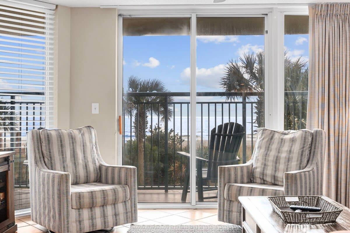 A balcony with two armchairs, a small table, and a wicker basket.