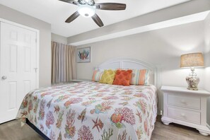 Ein Schlafzimmer mit Bett, Nachttisch, Deckenventilator und Tür.