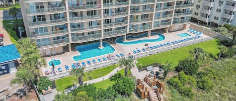 A multi-story hotel with a rooftop pool area, including lounge chairs and a small deck.
