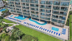 Un hotel de varios pisos con balcones, piscina y tumbonas.