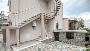 A building with a stone-paved entrance, a metal staircase, and a stone wall. - Terra di Meteora Suites 3 (Kalabaka)