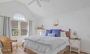 A bedroom with a bed, a chair, a nightstand, a window, and a ceiling fan. - Resort Style Beach Home! (Wildwood Crest)