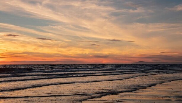 Une plage avec des vagues et un coucher de soleil.