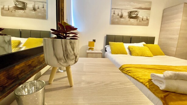 Habitación de hotel con una cama, una mesita de noche, un espejo y dos cuadros en las paredes.