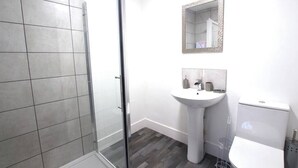 A modern bathroom with a glass shower enclosure, a pedestal sink, and a toilet.