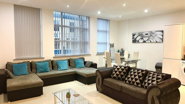 A living room with a sectional sofa, a glass coffee table, and a dining area with a table and chairs.