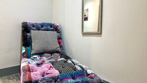 A small, neatly made bed with a colorful quilt and several pillows. A mirror hangs on the wall above the bed.
